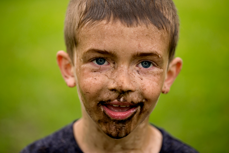 young boy covered in mud