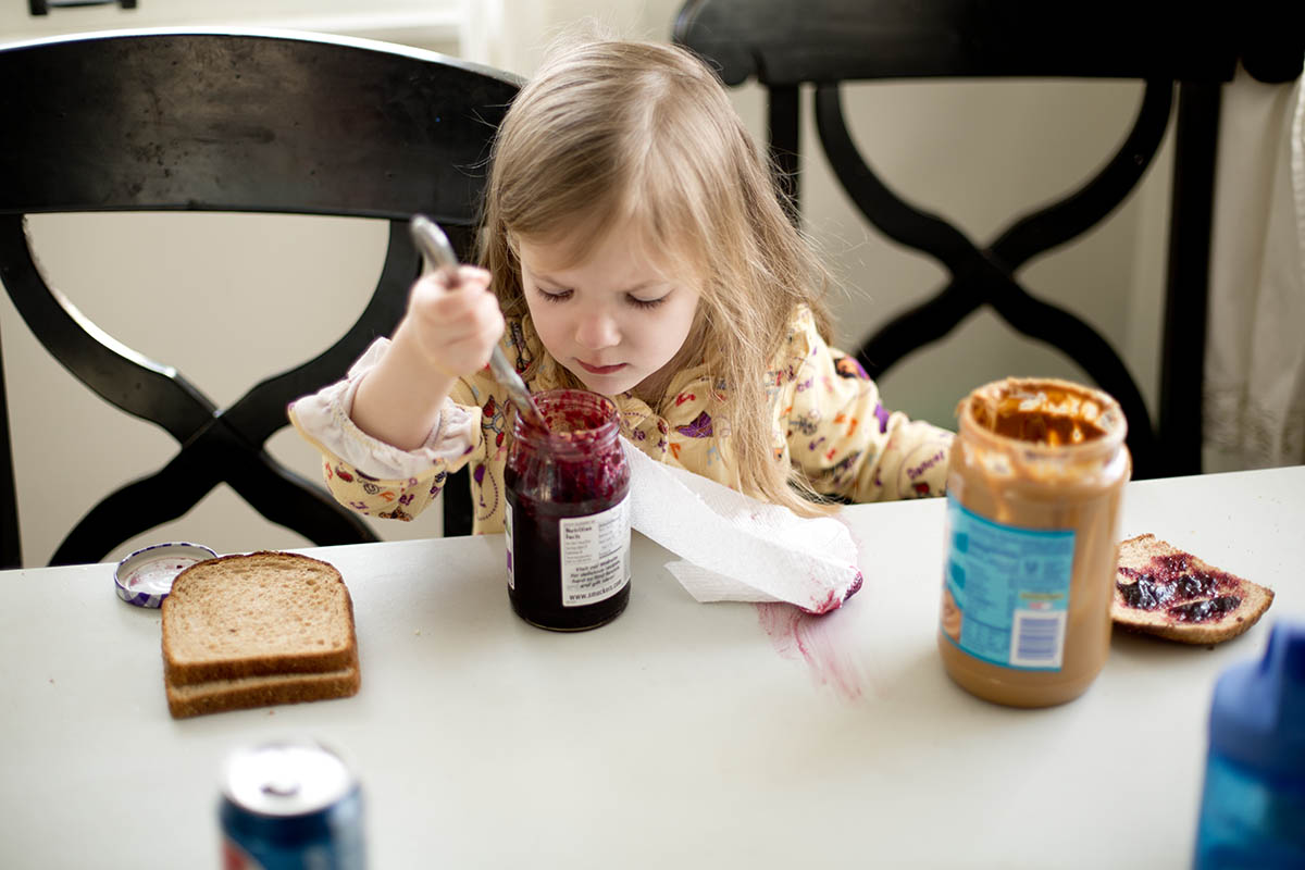 Little girl making her own Peanut Butter and Jelly sandwich at a core memory photo session