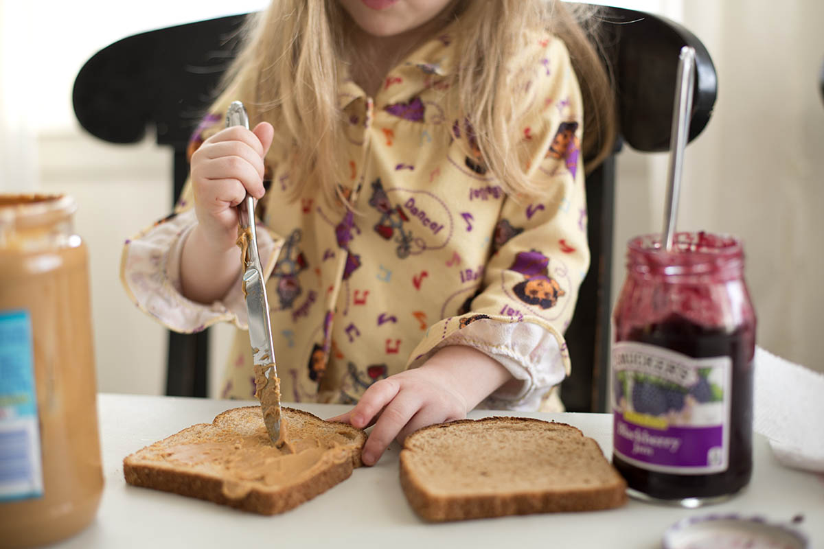 Little girl making her own Peanut Butter and Jelly sandwich at a core memory photo session