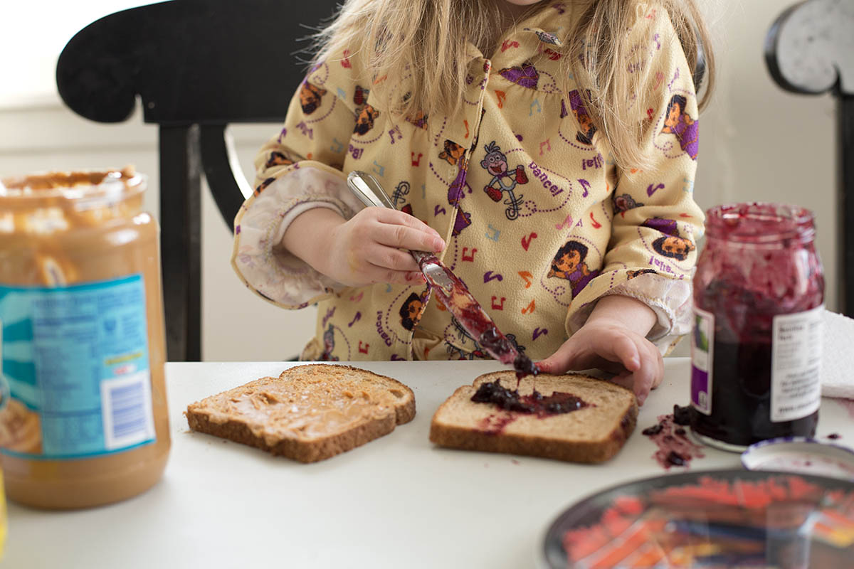 Little girl making her own Peanut Butter and Jelly sandwich at a core memory photo session