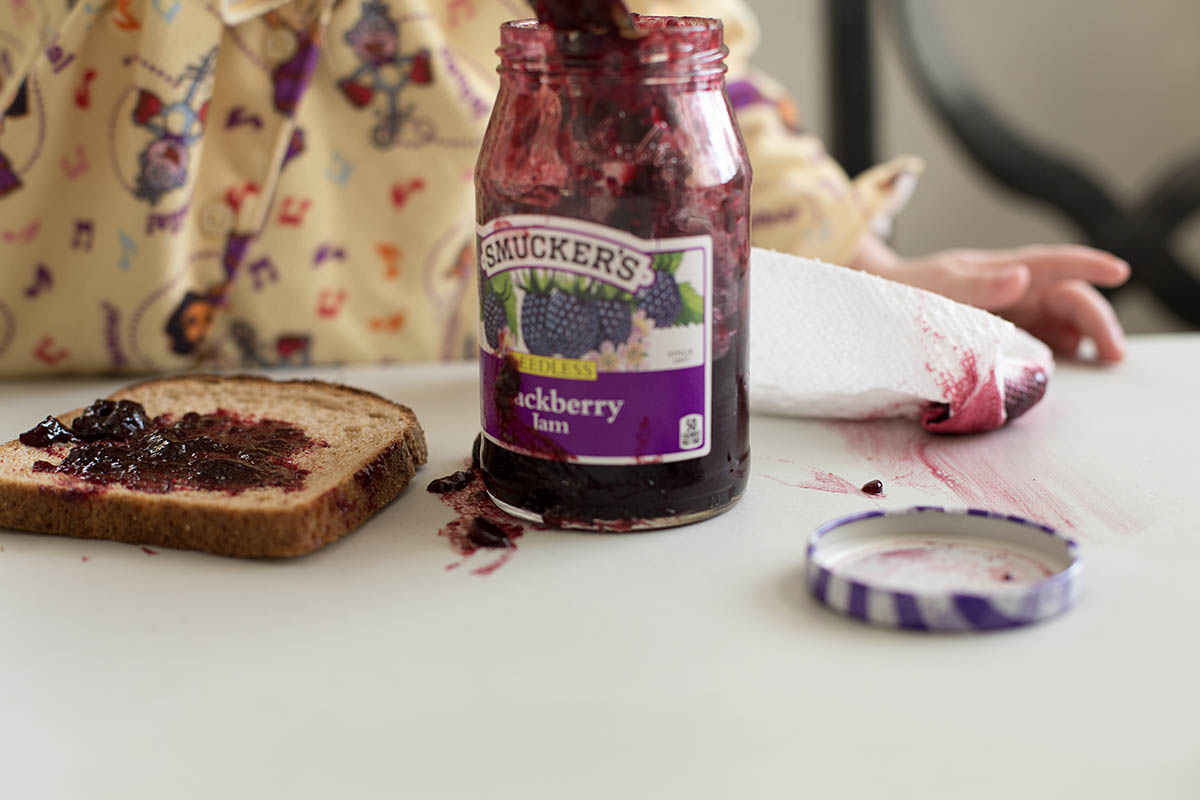 Little girl making her own Peanut Butter and Jelly sandwich at a core memory photo session