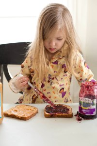 Little girl making her own Peanut Butter and Jelly sandwich at a core memory photo session