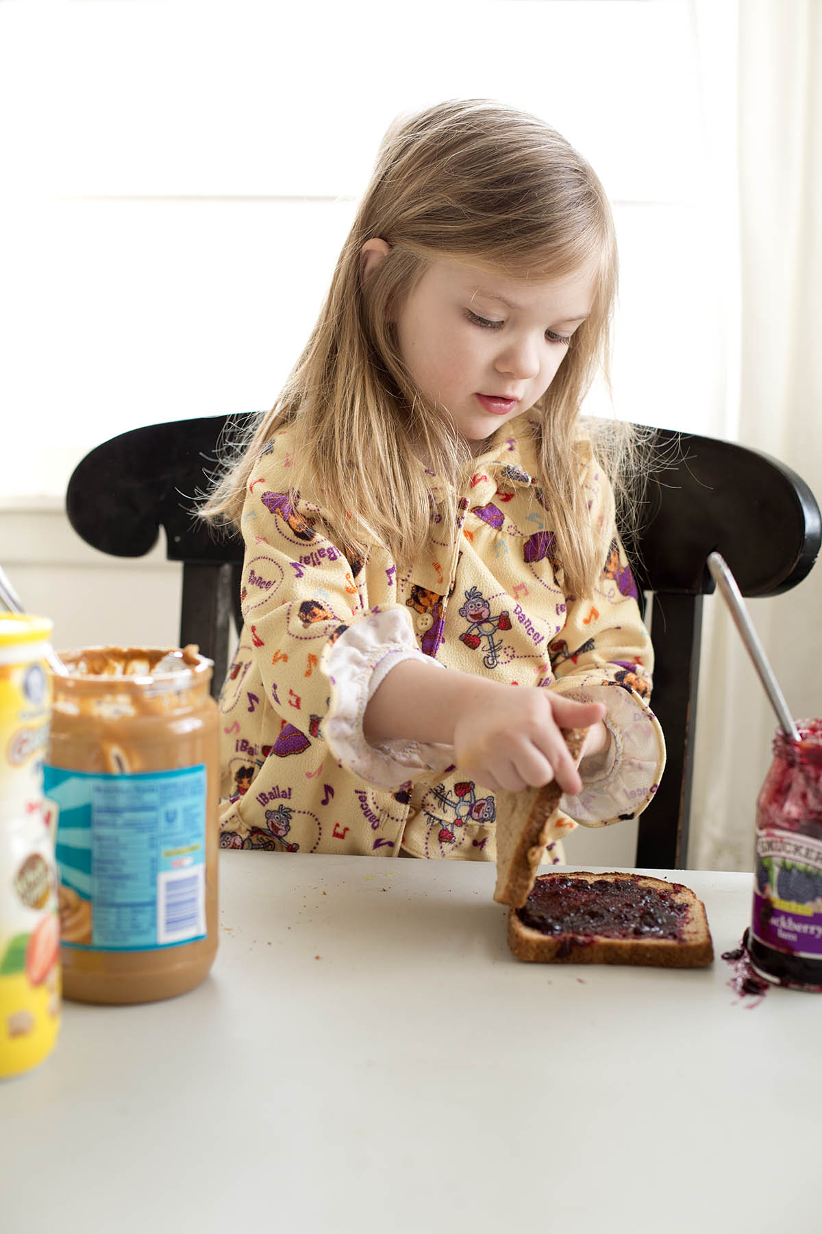 Little girl making her own Peanut Butter and Jelly sandwich at a core memory photo session