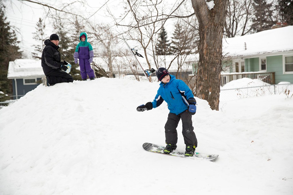 Young Boy Snowboarding in his backyard