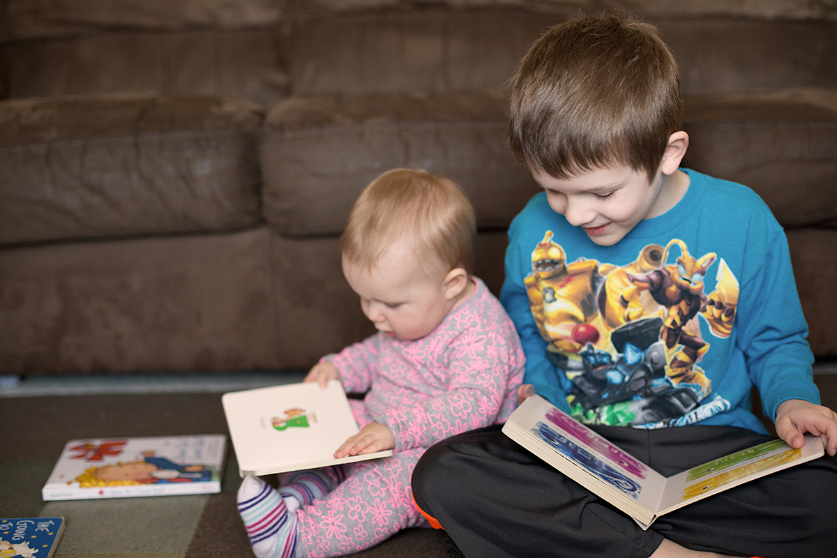 Sweet moment between siblings reading books together